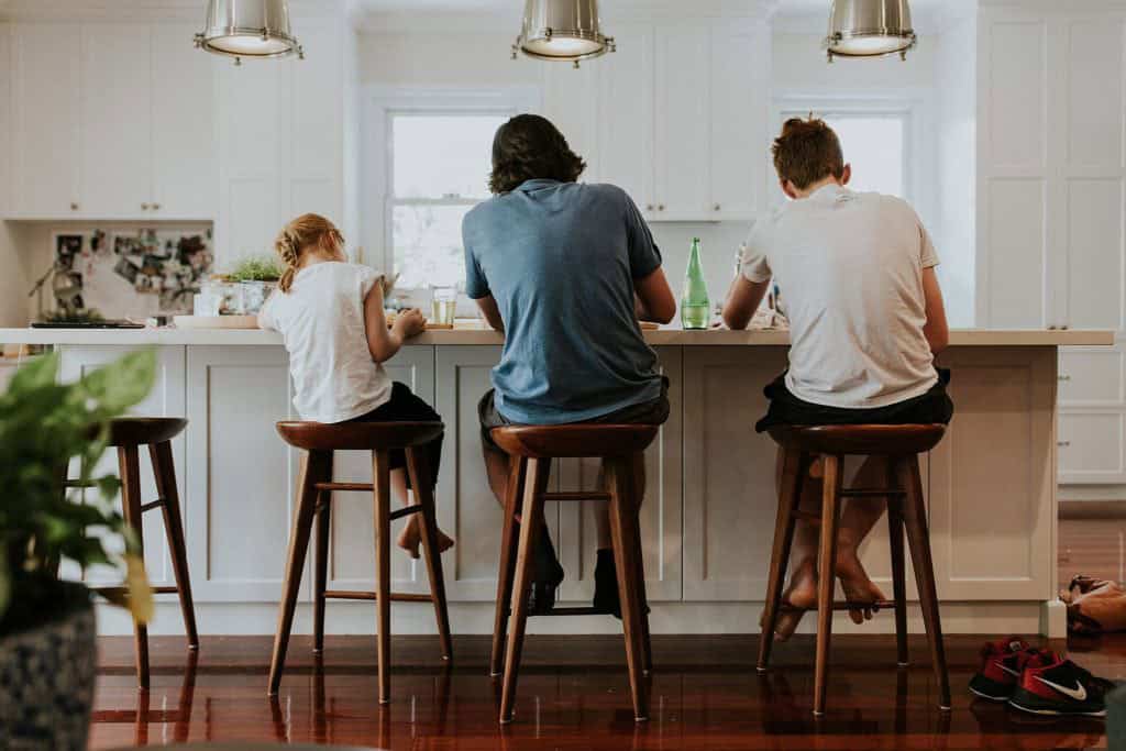 Family photo shoot with father and children sitting at kitchen bench