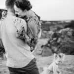 A husband scoops up his wife into his arms on the beach