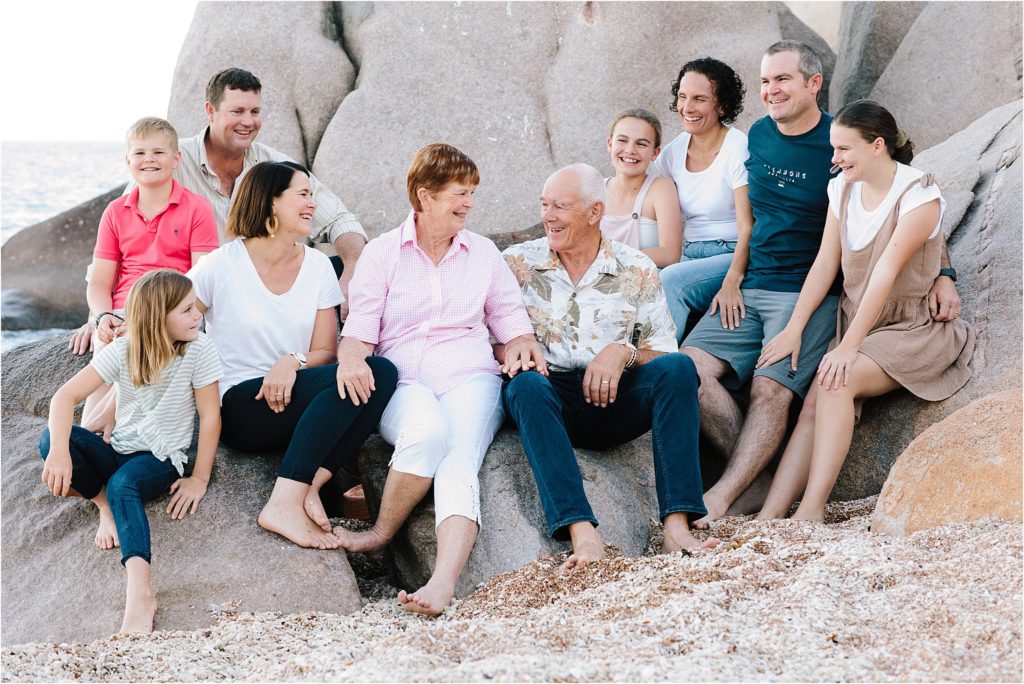 Family and grandparents on beach at Magnetic Island sitting on rocks.