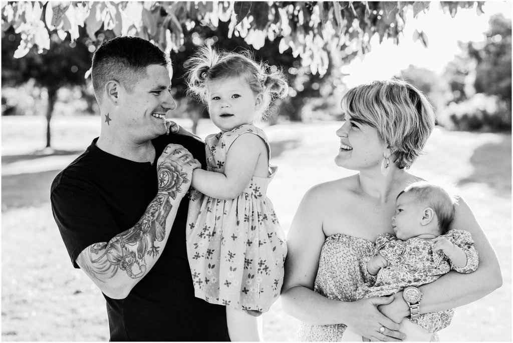Black and white family photo of husband and wife with two little girls.
