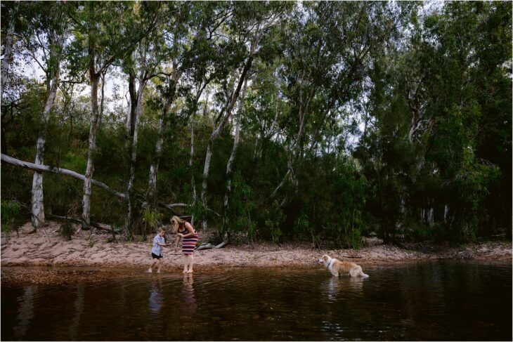 Emma and Lincoln look at rocks they find in the creek with their border collie.