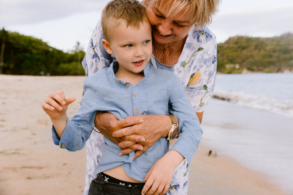 Grandmother cuddles her grandson on the beach