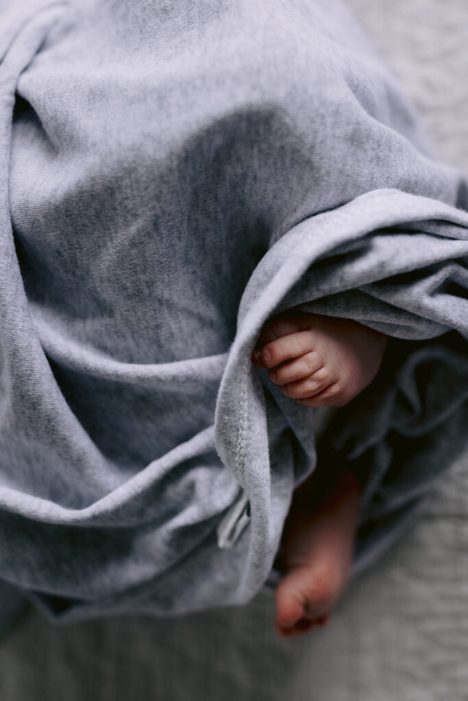 Tiny newborn feet wrapped in a grey wrap