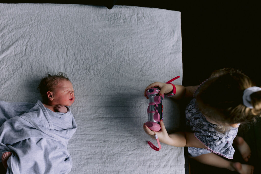 Big sister takes a photo of her newborn baby brother
