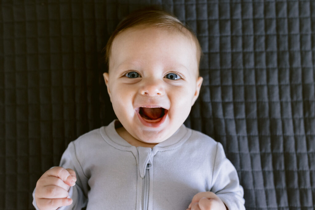 Baby Harvey smiles brightly with great joy.