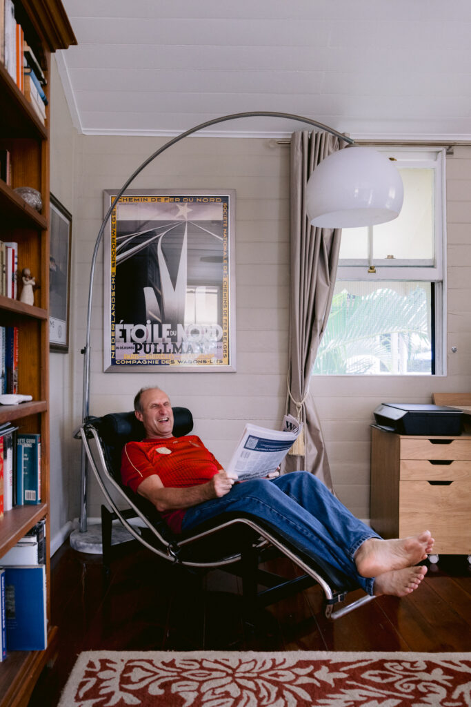 A natural photo of the Father sitting in his favourite chair relaxing and reading the Saturday Paper.