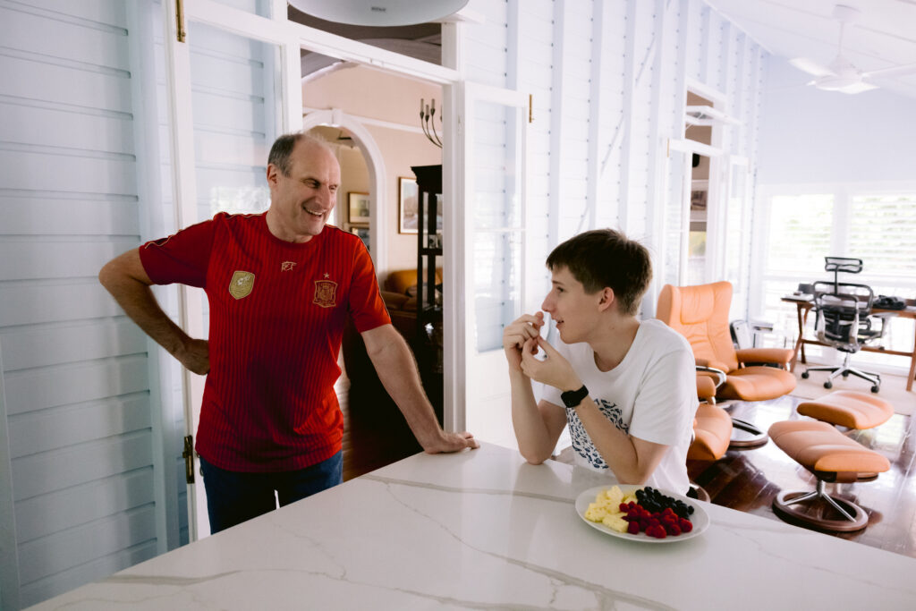 A natural photo of a father and his son having a relaxed conversation at the kitchen bench.