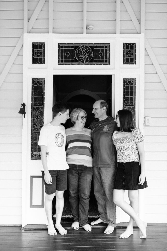 Family of four stand at the front door of their Queenslander House