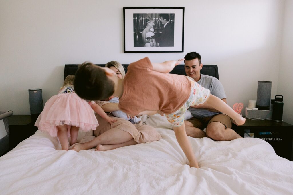 Siblings having fun jumping on their parents bed