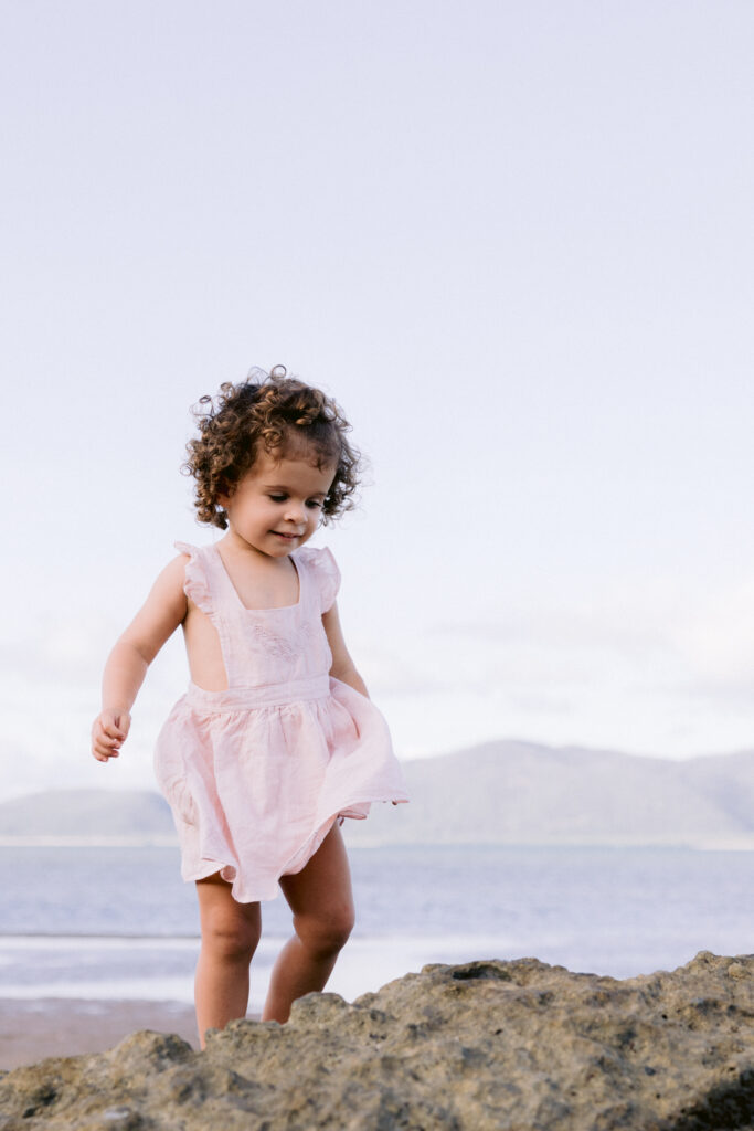A little girl has a joyful smile as she plays and adventures on the beach.