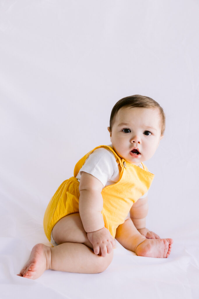 8 month old baby boy sitting on a studio backdrop