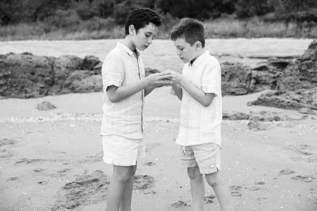 Brothers inquisitively examine a shell with a crab.