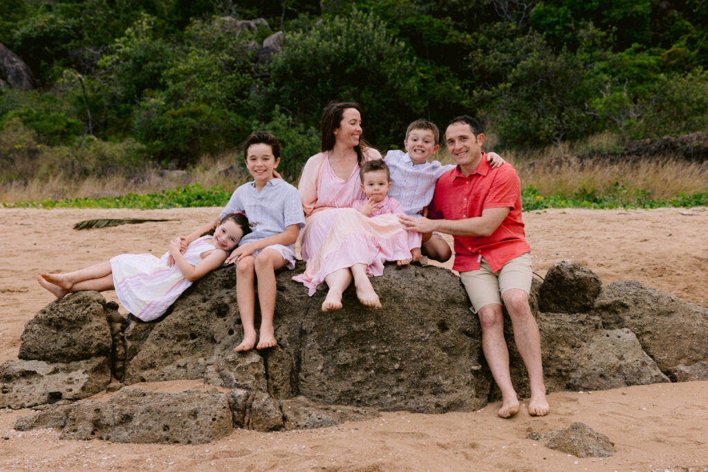 a relaxed portrait photo of a family of Mum and Dad and their four children at the beach