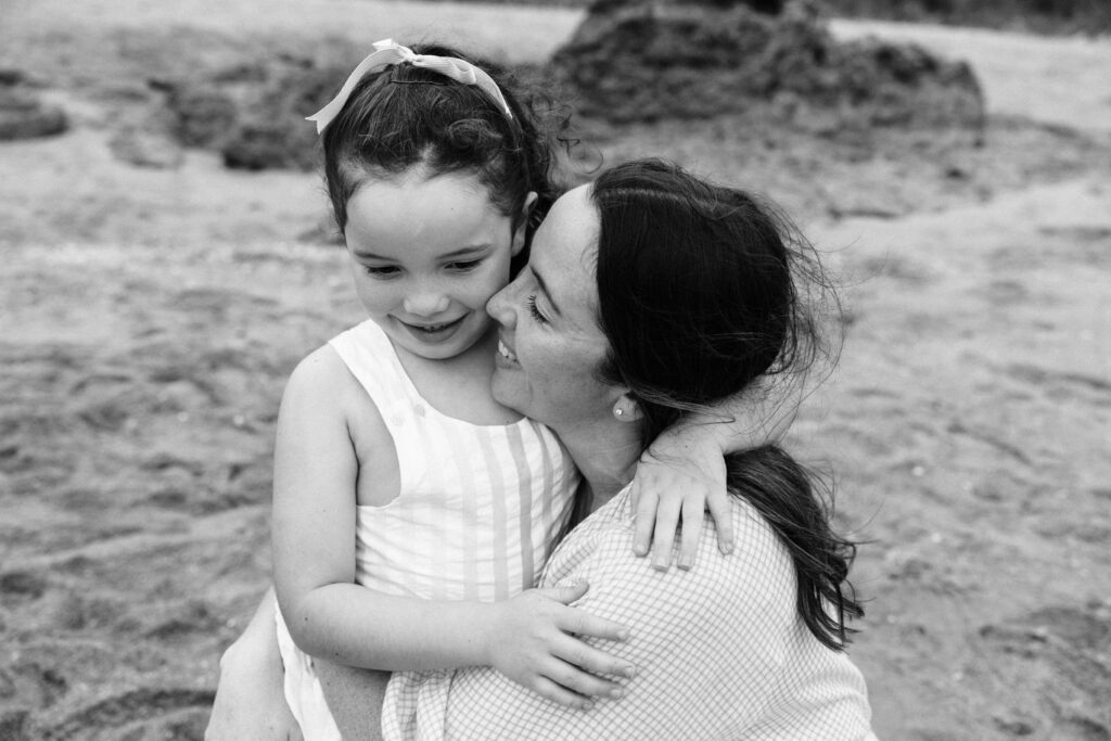 a black and white photo of Mum with her arms wrapped around her daughter. They are both smiling.