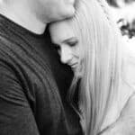 A husband has his arm around is wife as she rests her head on his chest