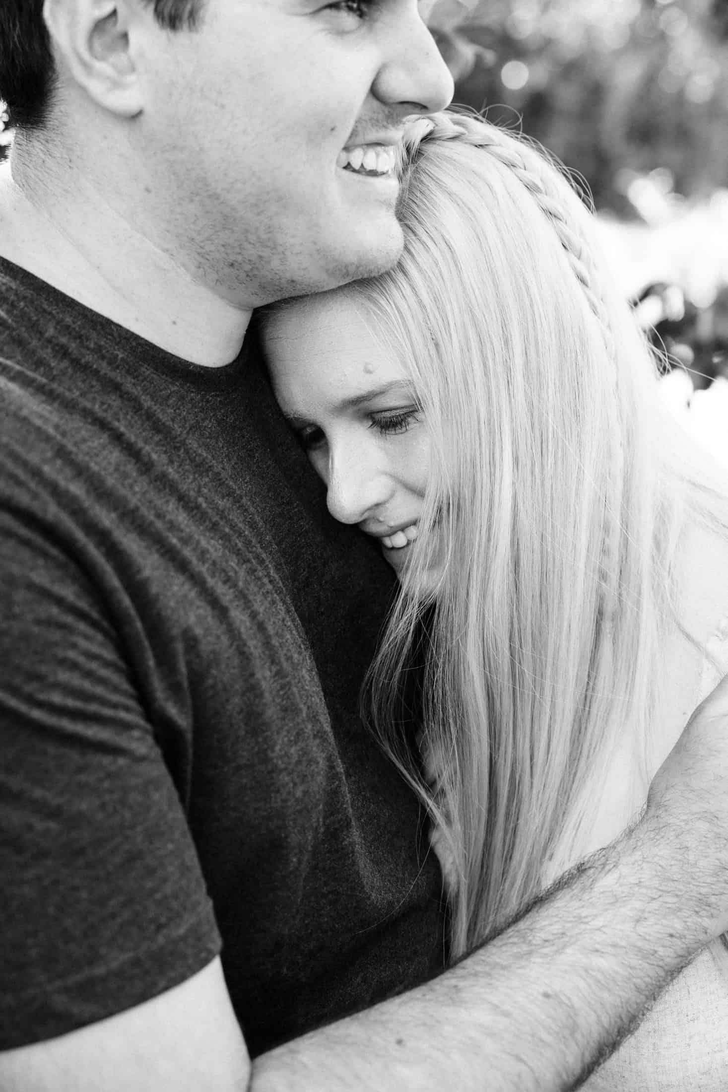 A husband has his arm around is wife as she rests her head on his chest