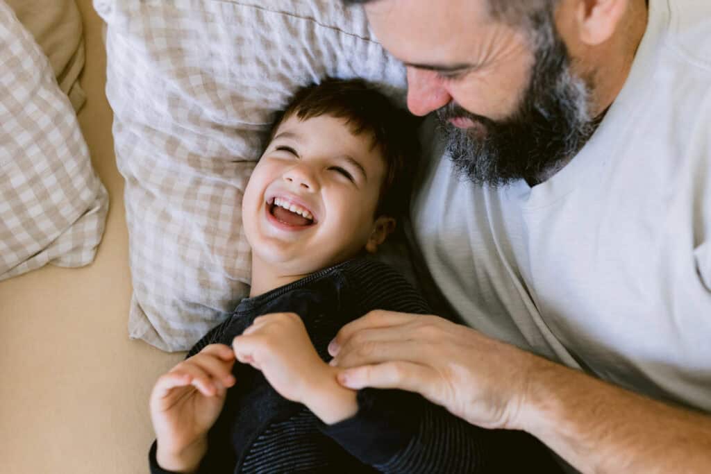 Dad is ticking his son playfully.