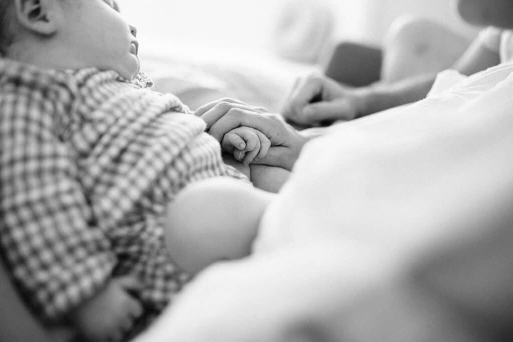 Mum is holding the newborn baby girl's tiny hand
