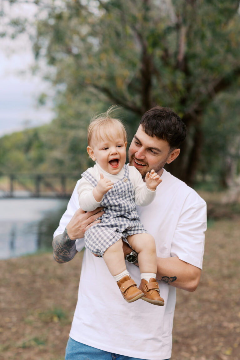 A father is holding his toddler and they are laughing
