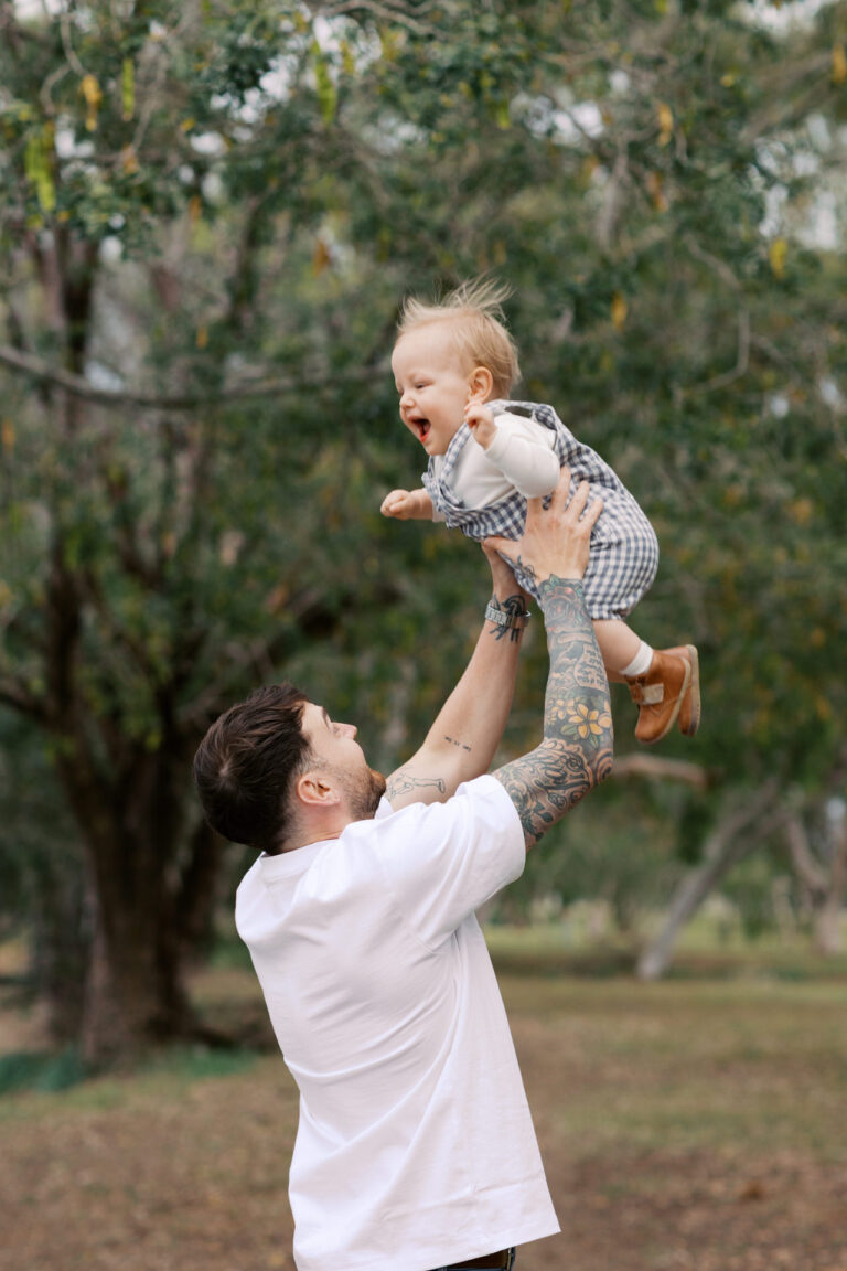 A dad playfully is throwing his toddler in the air