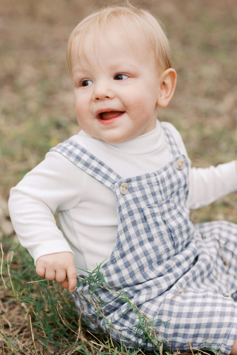a toddler is smiling sitting on the grass