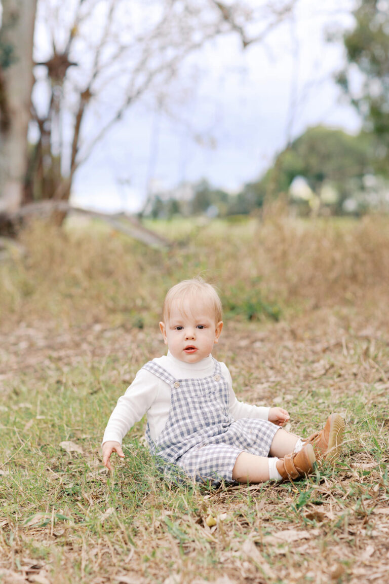 a toddler sits in the grass