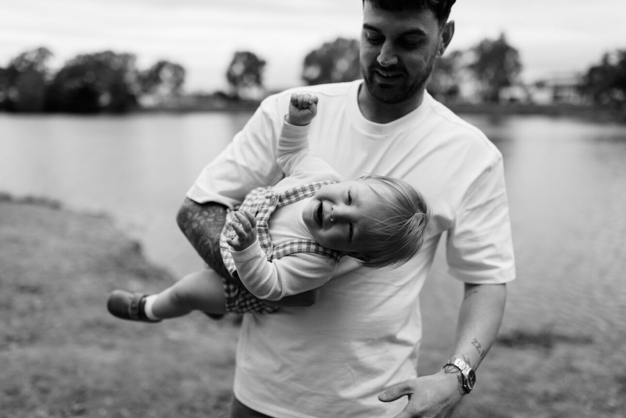 a father is playfully holding his toddler son while he laughs