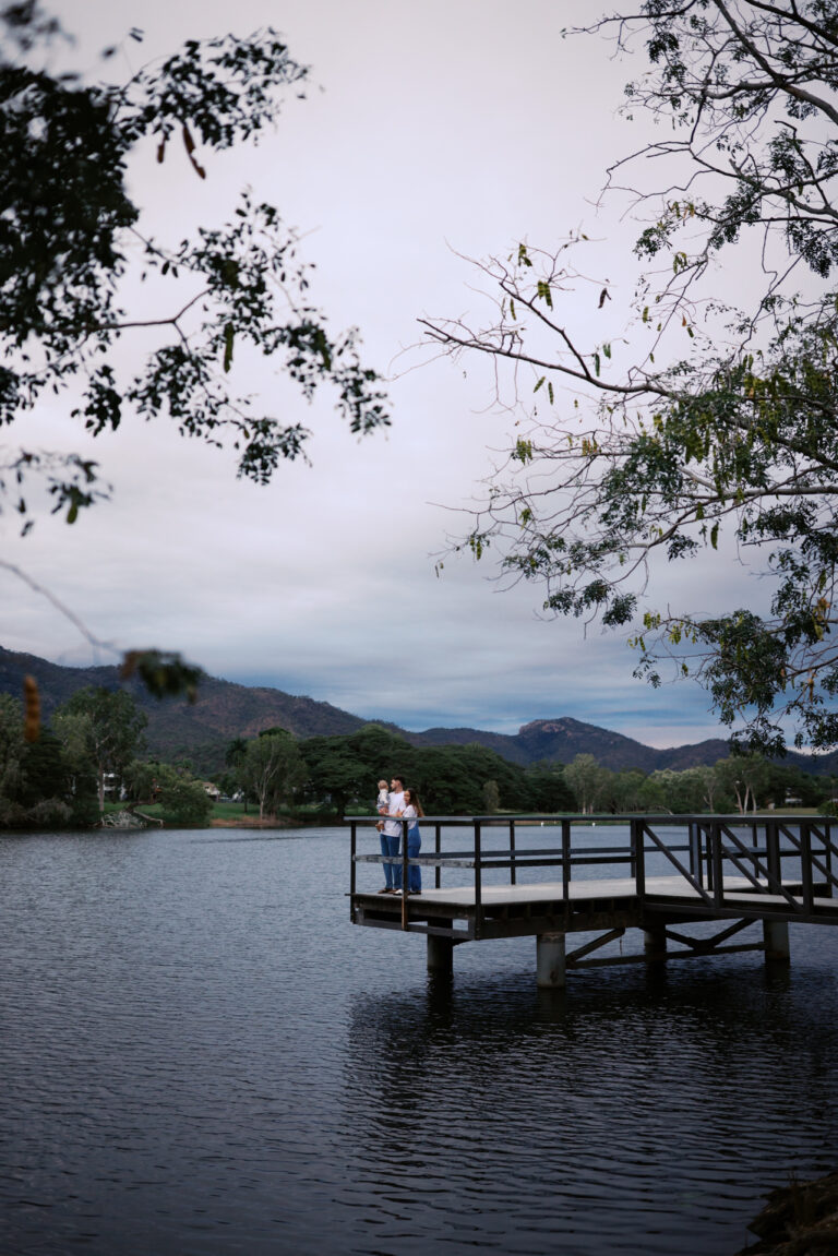 a mum and dad stand on a pontoon with their toddler son