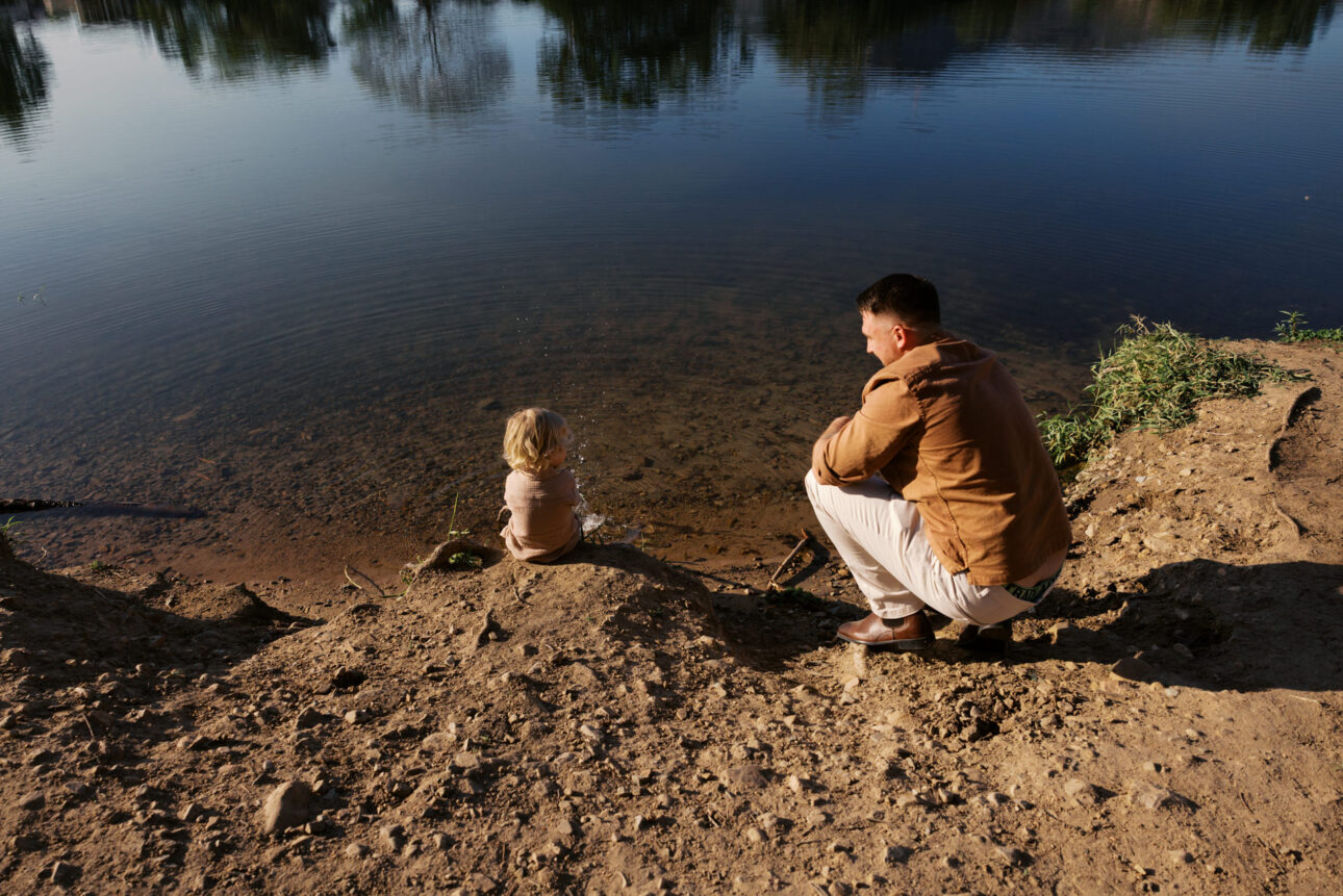 A father and his three year old sitting by the bank of a river