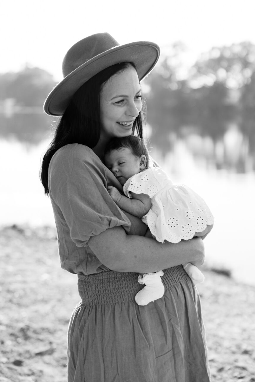 a black and white photo of a mum holding her newborn daughter smiling