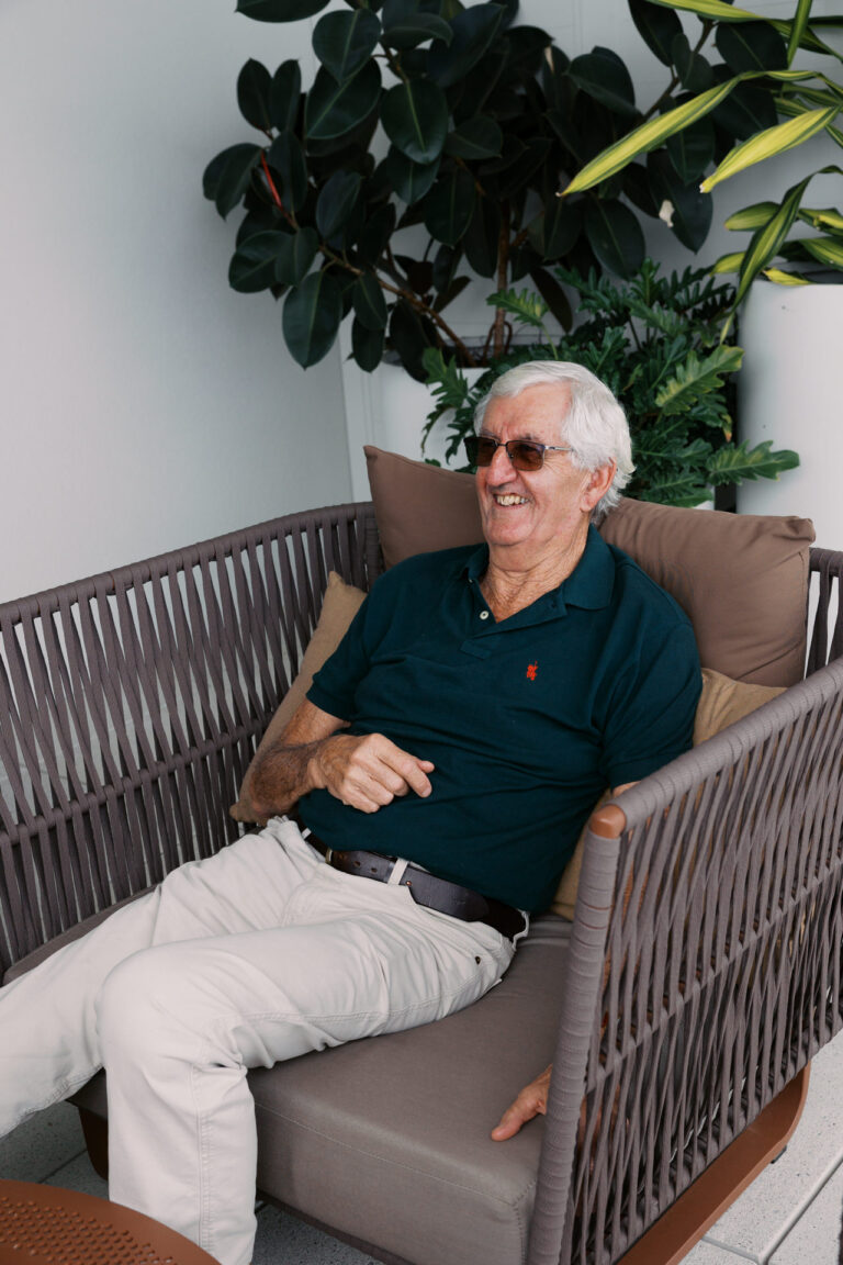A father sits in a chair and is smiling