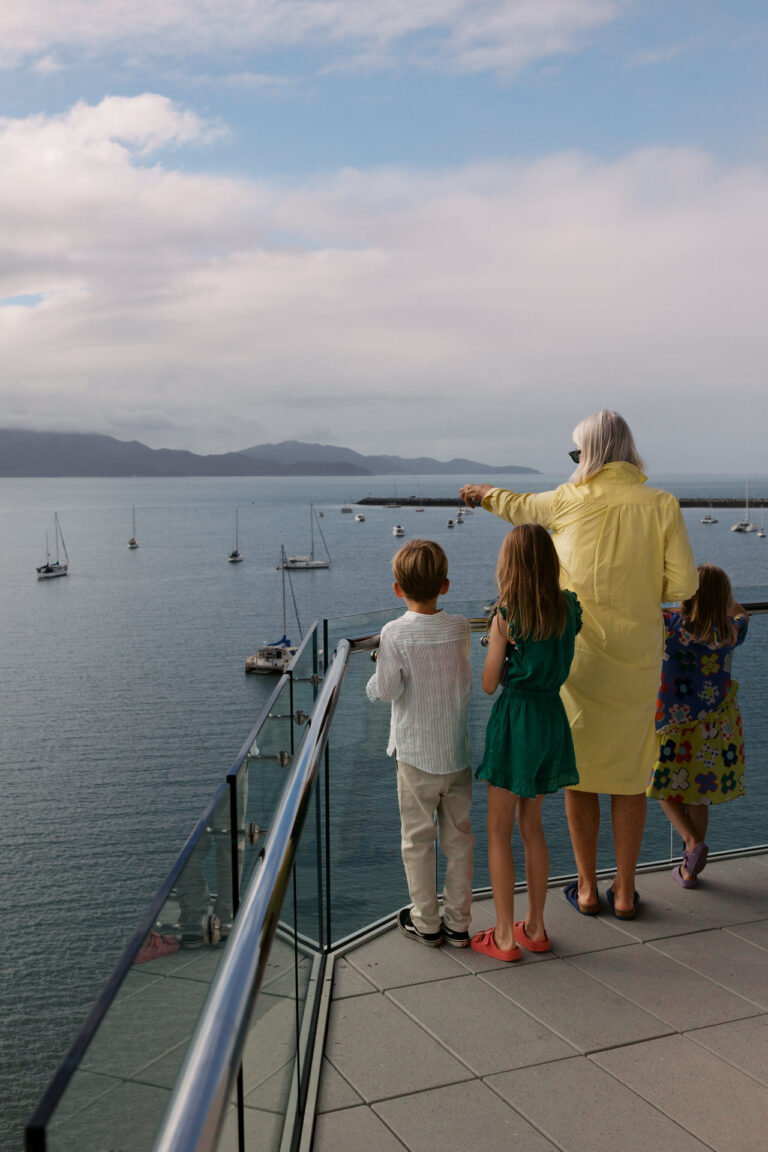 Grandma os pointing out at Magnetic island on the deck of Ardo with her Grandchildren