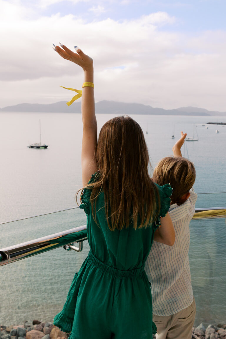 Two children wave at the boats from the balcony of Ardo