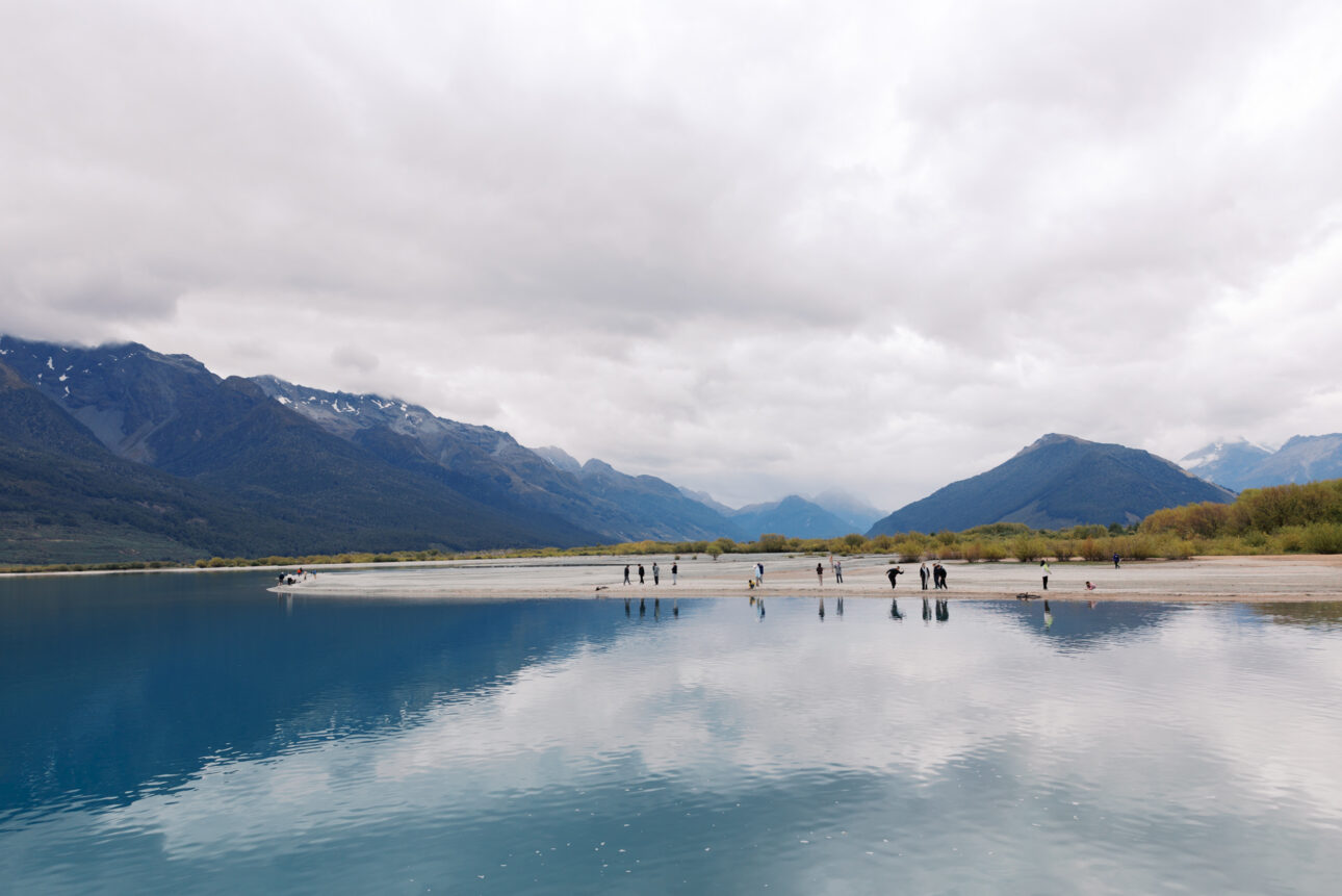 The lake at Glenorchy where people are standing and skimming stones.