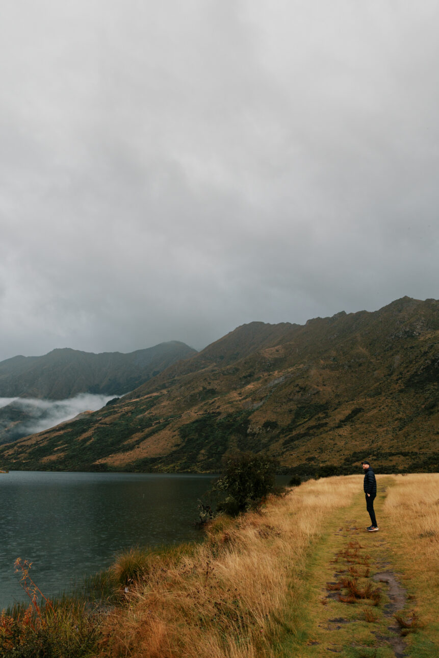 A man is standing by Moke Lake in Queenstown New Zealand