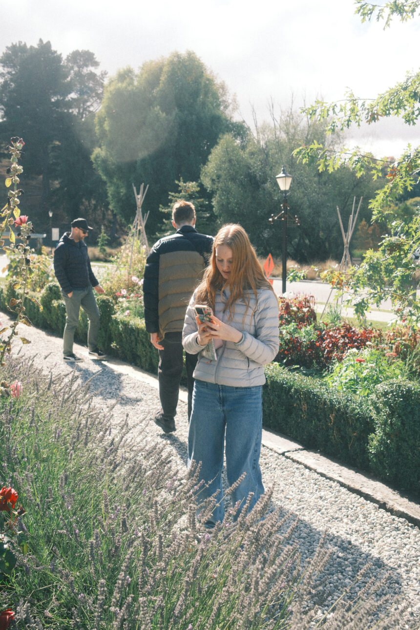 A young girl is taking a photo of the flower garden at Ayrburn Winery