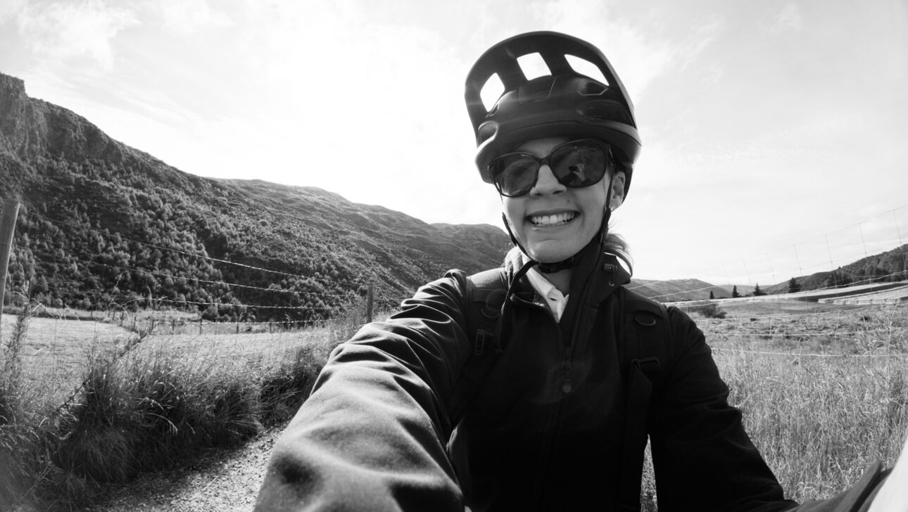 Katie is wearing a bike helmet as she rides an ebike from Gibbston Valley Bike hire along the river to arrow town