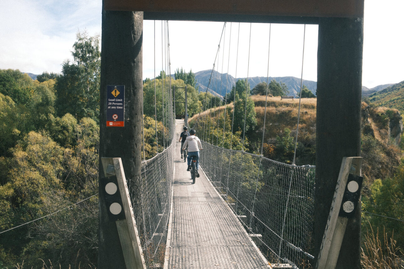 Suspension bridge in Queenstown. A young girl is riding across it