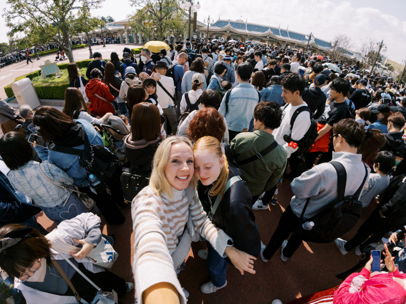 A mother and daughter are waiting for the park to open at Disney Tokyo. there is a great crowd