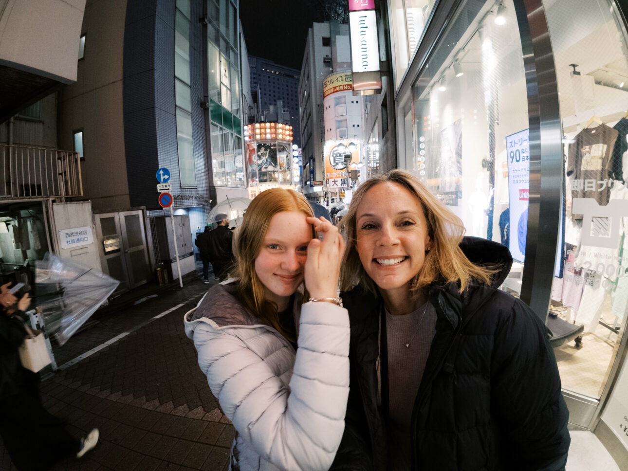 a photo of a mother and her teenage daughter in the streets of Shibuya at night.