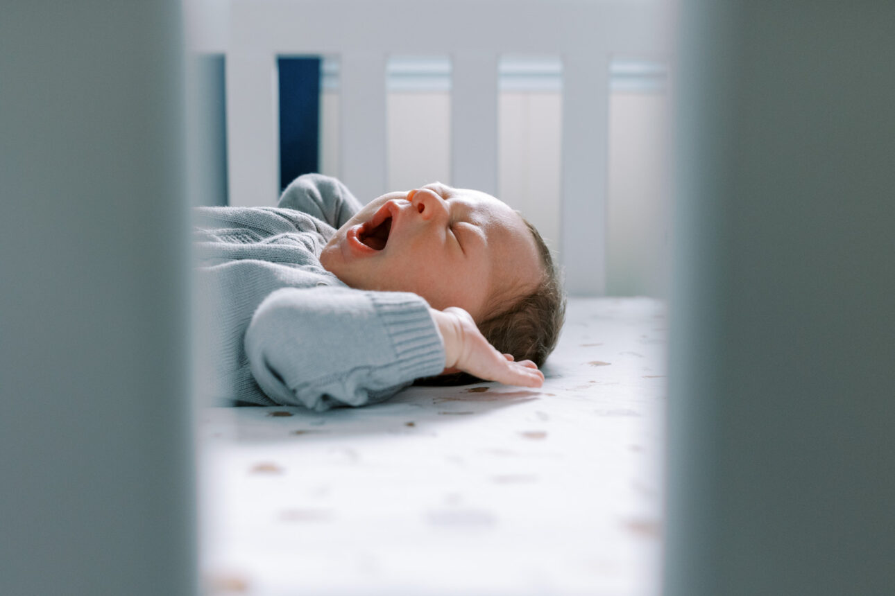 a newborn yawns in his cot
