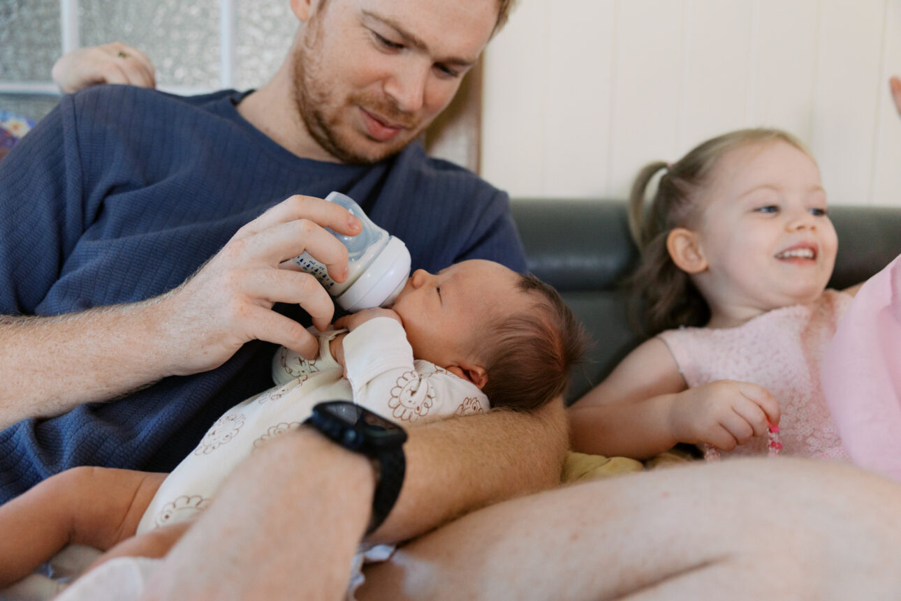 A father is feeding his newborn son a bottle
